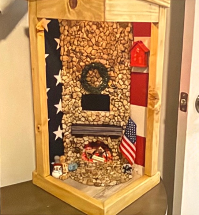 A miniature stone fireplace scene with small decorative details and American flag accents — the inside of the house, just as Justin imagined it.